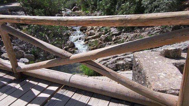 Wooden bridge over the river. Wooden footbridge spanning the stream. First person view. Rio Borosa. Spain.