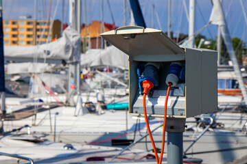 Charging station for boats at a marina pier in Finland, with electrical outlets where sailboats and motorboats are plugged in to charge while docked near the shore of the Baltic Sea