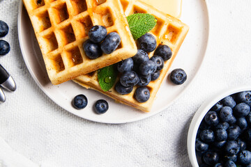 Waffles with blueberries, ice cream, and honey on a plate
