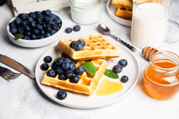 Waffles with blueberries, ice cream, and honey on a plate