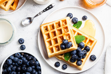 Waffles with blueberries, ice cream, and honey on a plate