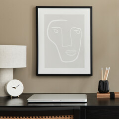 Stylish composition of home office interior with black wooden desk, chair, dried flower in vase, laptop, mock up poster frame, design table lamp, clock and elegant office accessories. Template.