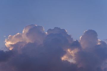 Serene Evening Clouds with Golden Edges Backlit by Sunset in a Tranquil Blue Sky