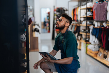 Bicycle shop worker checking inventory with digital tablet