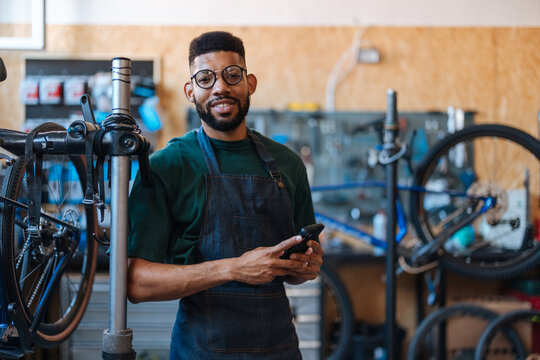 Bicycle mechanic using smartphone in repair shop