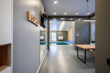 modern interior with a view to an indoor pool. Neutral tones, tile floors, wooden accents, and sleek furniture give a stylish, tranquil feel