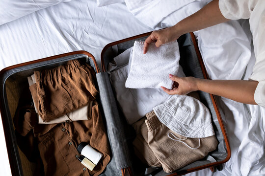 Woman packing suitcase with clothes and accessories for travel