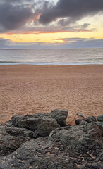 Sunrise kisses tranquil beach, whispering serenity, balancing jagged rocks and soft sand; celebrate Earth Day and World Ocean Day