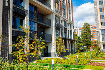 A modern residential complex with an elegant facade, balconies with decorative railings and well-kept green spaces creates a cozy and stylish atmosphere.