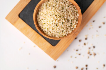 Hemp seeds in wooden bowl on light background. Superfood, natural organic seeds for healthy eating, source of protein, vitamins and omega 3. Healthy food concept