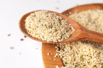 Hemp seeds in wooden spoon and bowls on light background. Superfood, healthy tasty organic hemp seeds, source of omega 3, protein, flat lay top view. Supplement to healthy diet