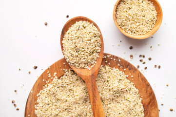 Hemp seeds in wooden spoon and bowls on light background. Superfood, healthy tasty organic hemp seeds, source of omega 3, protein, flat lay top view. Supplement to healthy diet
