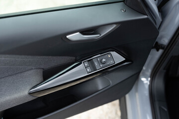 Naklejka premium Door handle with power window control. Window control buttons in modern luxury electric car. Car leather interior details of door handle with windows controls and adjustments. Car window controls
