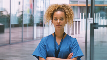 Portrait Of Serious Female Nurse Wearing Scrubs Standing In Modern Hospital Building © Monkey Business