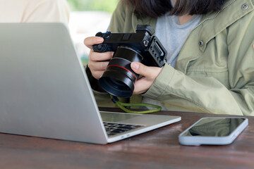 Woman checks photos on her digital camera with a laptop by her side, working or editing images.