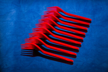 Abstract still life with red forks on blue table