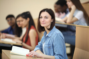 education, high school, university, learning and people concept - group of international students with notebooks writing at lecture hall