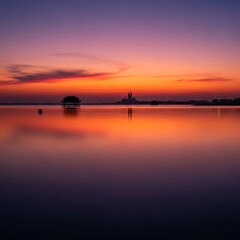 A tranquil sunrise over a still lake, featuring a silhouette of a structure on stilts.