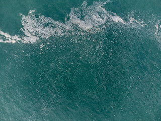 Wonderful tropical beach with blue water and orange sand forming small waves seen from above