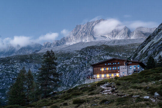 A scenic view of a mountain river flowing over rocks under a starry sky. Val di Fumo, Chiese river, Carr&egrave; Alto, Trentino. Lights from the Fumo Refuge are visible in the distance.