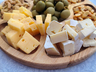 a plate of cheese, nuts, olives, a delicious snack on the table. healthy food. background for the design.