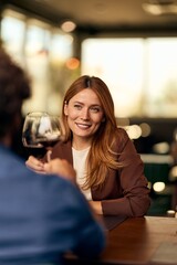 Smiling Woman Enjoying Wine During a Conversation in a Cozy Restaurant Setting