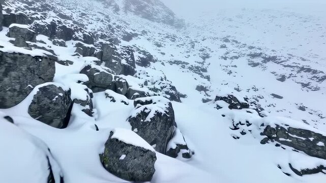 Serene winter landscape showcasing snow-covered rocks and hills amidst light fog