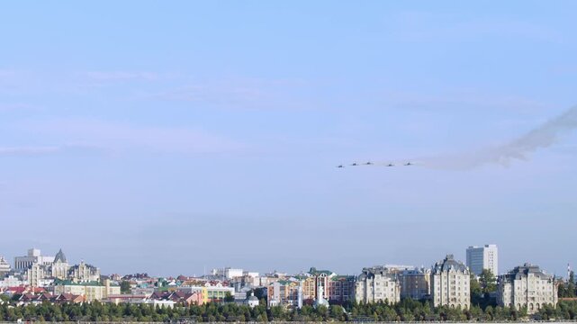 Several small combat training aircraft flew over urban landscape, performing aerobatic maneuvers in spectacular fashion. They flew in different directions, creating breathtaking aerial show.