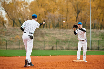 Obraz premium Two teenage boys engage in an exciting baseball practice on a sunny afternoon field