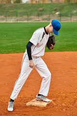 Skillful teenage boy prepares for a pitch on a bright baseball field at dusk