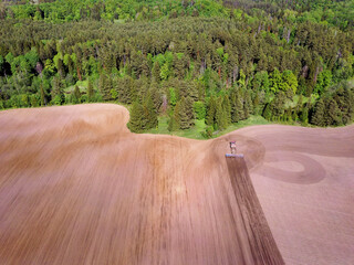 Aerial view landscape with plowed fields and tractor and forest on spring sunny day