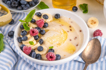 Sweet breakfast farina porridge with butter, honey and fruits. American creamy milled wheat flour porridge, hot breakfast cereal