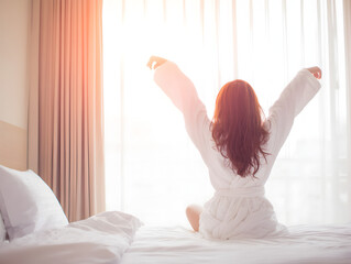 Bright hospitality scene guest in robe greets sunrise on bed ideal booking hero image and travel ad