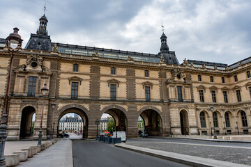 Fototapeta premium Classic architecture of the Louvre Museum, featuring a long arcade and ornate details under a cloudy sky