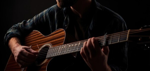 Obraz premium The musician passionately playing an acoustic guitar in a dark setting.