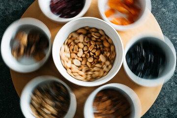 Dynamic Array of Colorful Snack Bowls with Assorted Nuts and Dried Fruits on a Swirling Tabletop