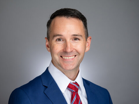 Portrait of white male professional in a blue suit and red tie. 