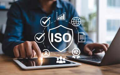 Person using tablet and laptop with ISO quality management digital overlay standard certification