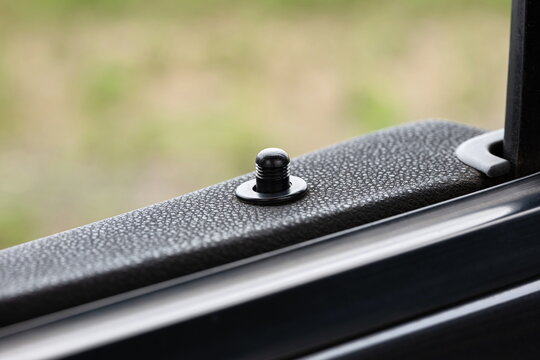 Car door lock knob or pin on the top of the door card. Close up, macro shot, shallow depth of field, no people