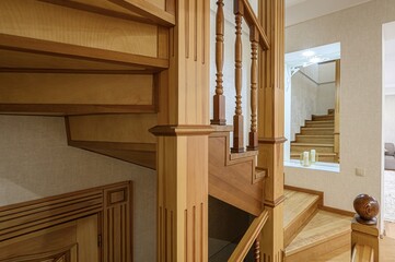 Warm-toned wooden staircase with decorative balusters and a framed view to another set of stairs. Elegant design, neutral wall colors