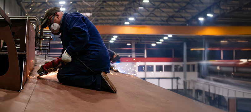 A man in a blue jacket is working on a piece of metal - Powered by Adobe
