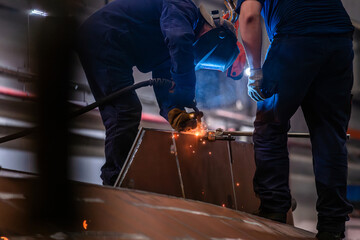 Two men are working on a project, one of them is wearing a helmet