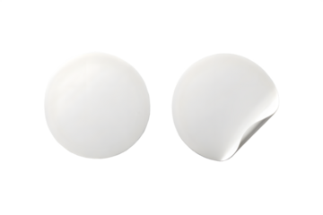 Two blank white round stickers, one peeling off, isolated on transparent background