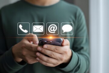 Person holding a smartphone displaying glowing contact icons for phone email at symbol and chat message for communication and customer service