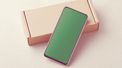 Green screen mobile phone resting against cardboard box, ready for digital content mockup or design presentation