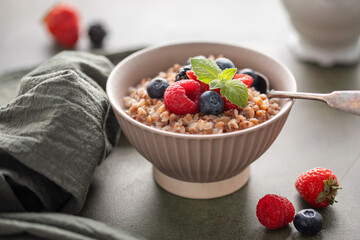 Milk sweet buckwheat porridge with berries in a bowl on the table. Healthy breakfast
