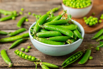 Fresh green pea pods with green peas on a wooden background. Sweet green peas. Green pea beans vegetables. Vegan. healthy vegetable. Copy space