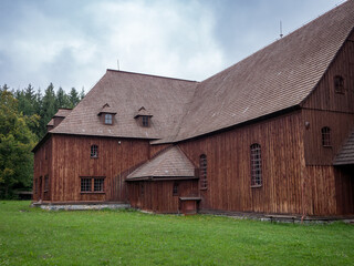 Fototapeta premium Side view of the wooden articular church in Svätý Kríž, Slovakia. Historic Lutheran church built from timber without nails, surrounded by green grass and trees.