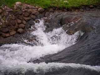 Detail of artificial whitewater rapids in Liptovsk&yacute; Mikul&aacute;&scaron;, Slovakia, with visible water turbulence and stone riverbank used for kayaking and canoe training.