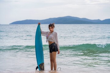 Young woman enjoying a day of surfing on a beach with clear waters and distant mountains